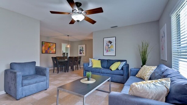 A modern living room with a blue sofa, a coffee table, and a ceiling fan.