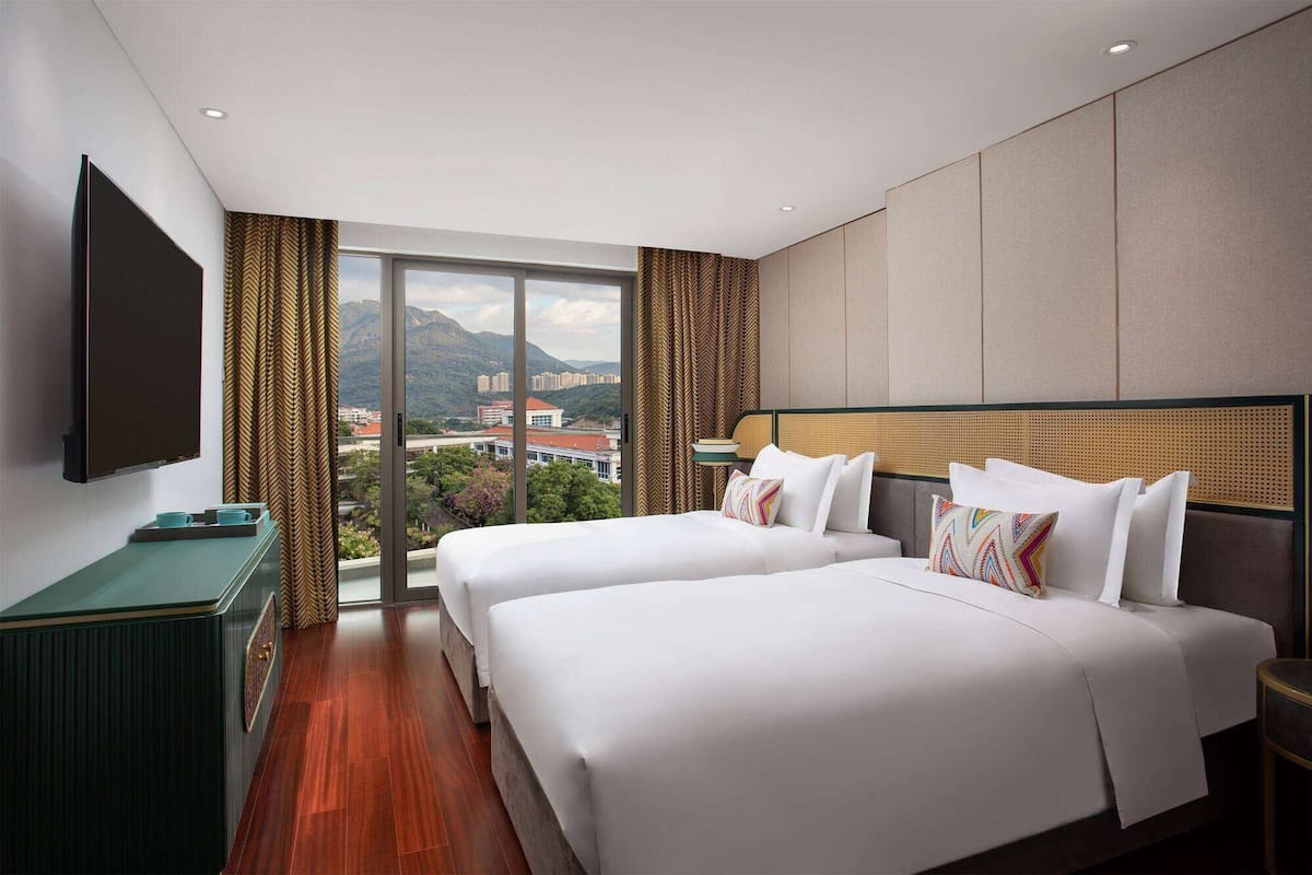 Habitación de hotel con dos camas, televisión y vistas a las montañas.