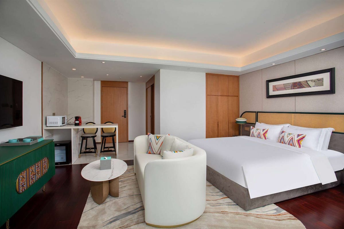 Habitación de hotel con cama, sofá, una mesita, televisor y microondas.