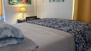 Un dormitorio con una cama, una mesita de noche con lámpara y dos unidades de aire acondicionado fijadas a la pared.