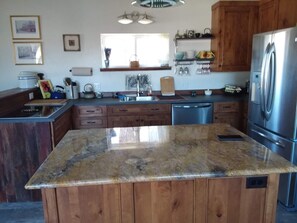 Una cocina con armarios de madera, un refrigerador de acero inoxidable y una encimera de granito.