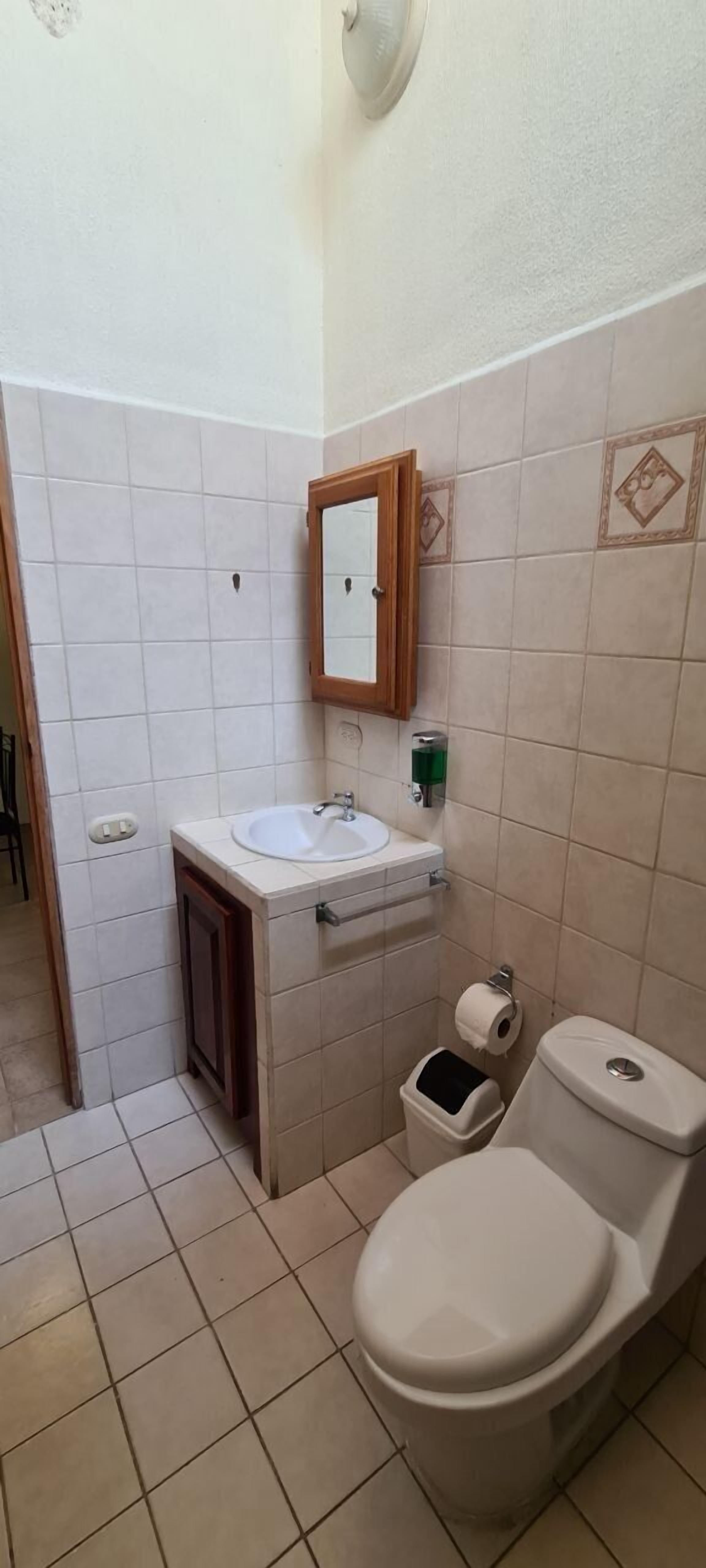 Une petite salle de bain avec des toilettes, un lavabo et un miroir.
