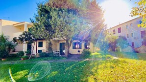 Une cour avec un arbre, un bâtiment doté d’un balcon et un ciel dégagé.