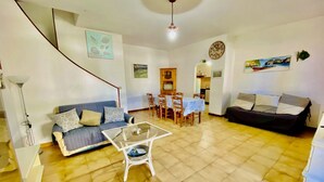 Un salon comprenant un canapé, une table basse en verre et un coin repas avec une table et des chaises.