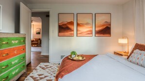 Et hotelværelse med en seng, en kommode, en lampe og tre billeder på væggen.