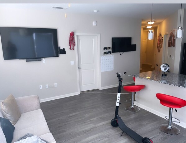 Relax in this stylish living space with a flat-screen TV, comfortable sofa, and modern bar stools.