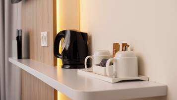 A modern kitchenette with a coffee maker, two white mugs, and a tray of coffee pods.