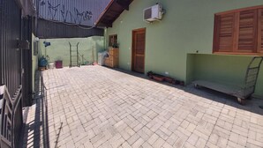 A courtyard with a tiled floor, a green wall, a wooden door, and a window with shutters. - Cozy house with 2 garages and 2 bedrooms. (SP)
