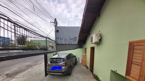 A car parked in a narrow alleyway with a green building on one side and a metal fence on the other. - Cozy house with 2 garages and 2 bedrooms. (SP)