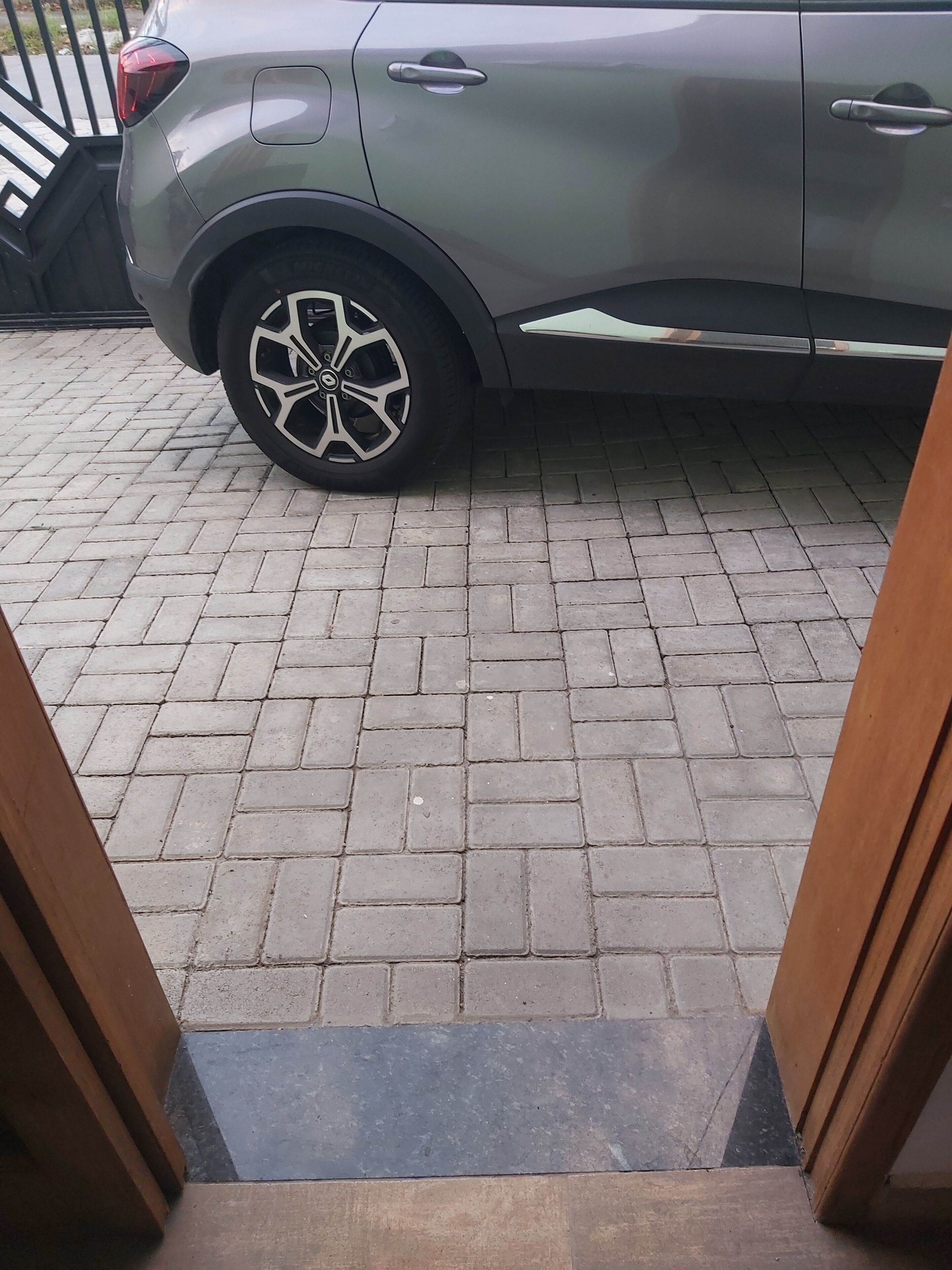 A car parked on a paved area with a metal fence in the background.