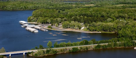 An aerial view of a lakeside property with a dock, a bridge, and a parking area.