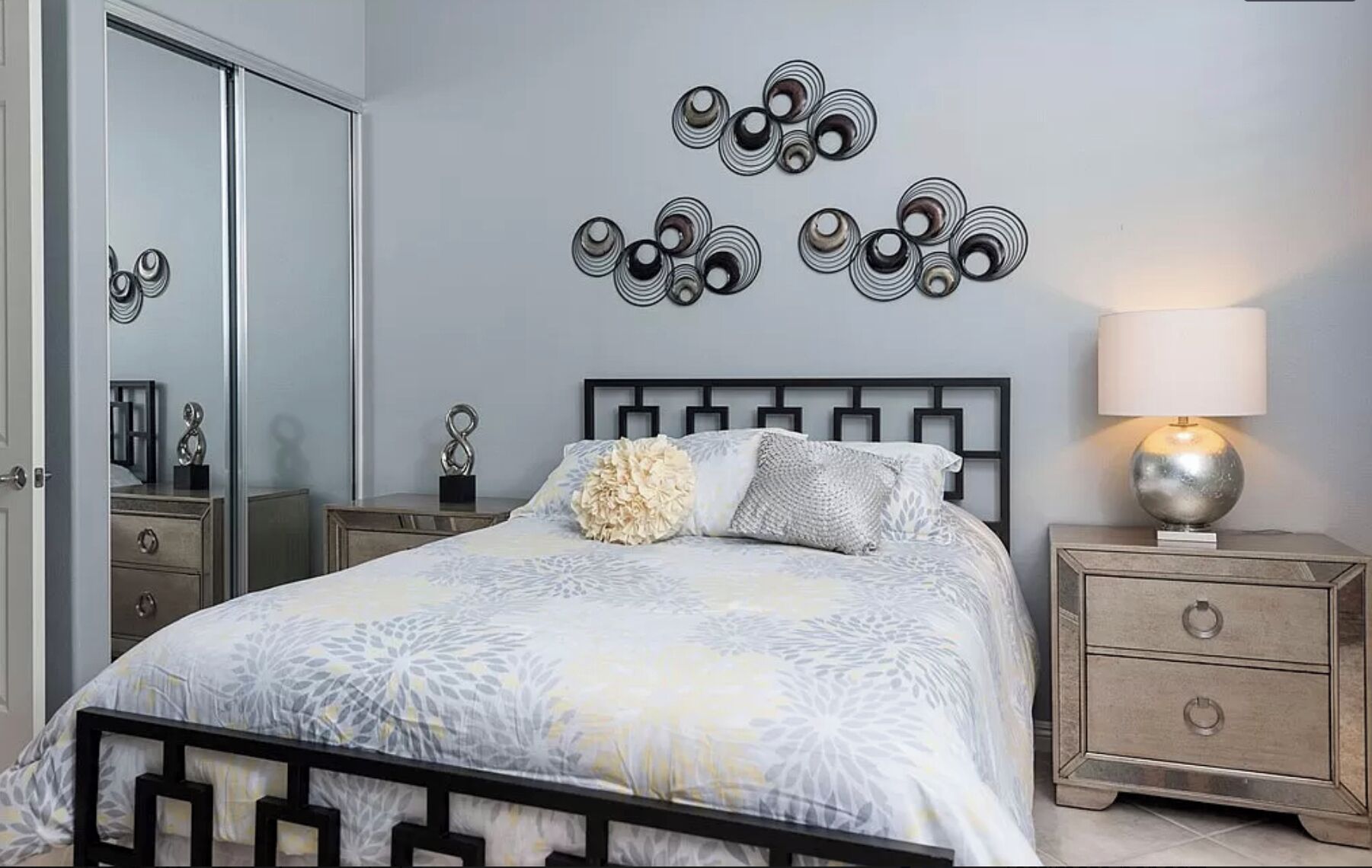A bedroom with a bed, a nightstand, a lamp, a dresser, and a mirror.