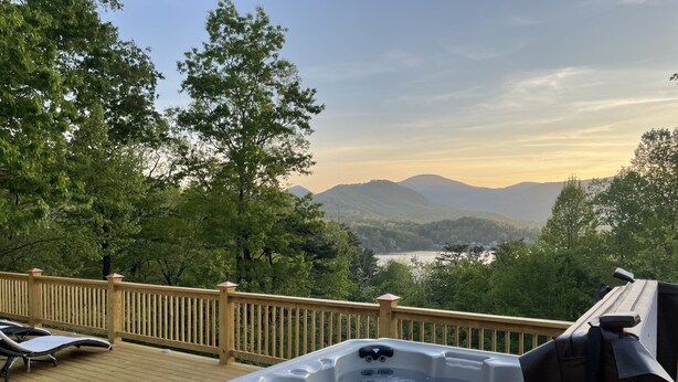 Ein Whirlpool auf einer Holzterrasse mit Blick auf einen See und Berge.