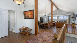 Ein geräumiger Loft mit hohen Decken, einem Essbereich mit großem Tisch und Stühlen sowie einer gemütlichen Sitzecke mit einer Couch und einer Treppe mit Holzbalkon.