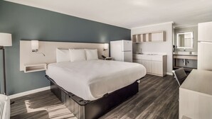 Une chambre d’hôtel moderne dotée d’un grand lit, d’un bureau intégré et d’une kitchenette.