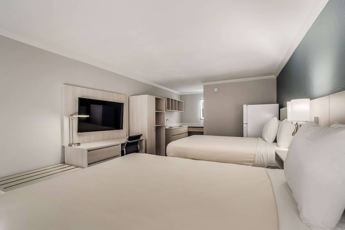 Een hotelkamer met twee bedden, een televisie, een bureau en een kledingkast.