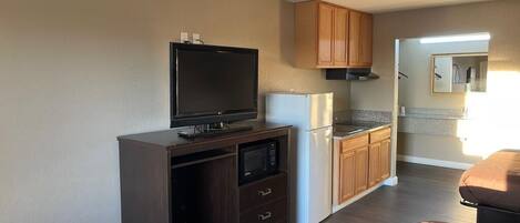 Un espacio habitable compacto con kitchenette, televisor de pantalla plana y microondas.