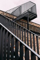 Uma escadaria com grades de metal preto que leva a um edifício de tijolos.