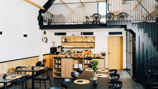 A modern restaurant with a high ceiling, wooden accents, and a mezzanine level. - Factory Hotel (Beveren)