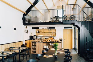 Um restaurante moderno com teto alto, detalhes em madeira e um mezanino.