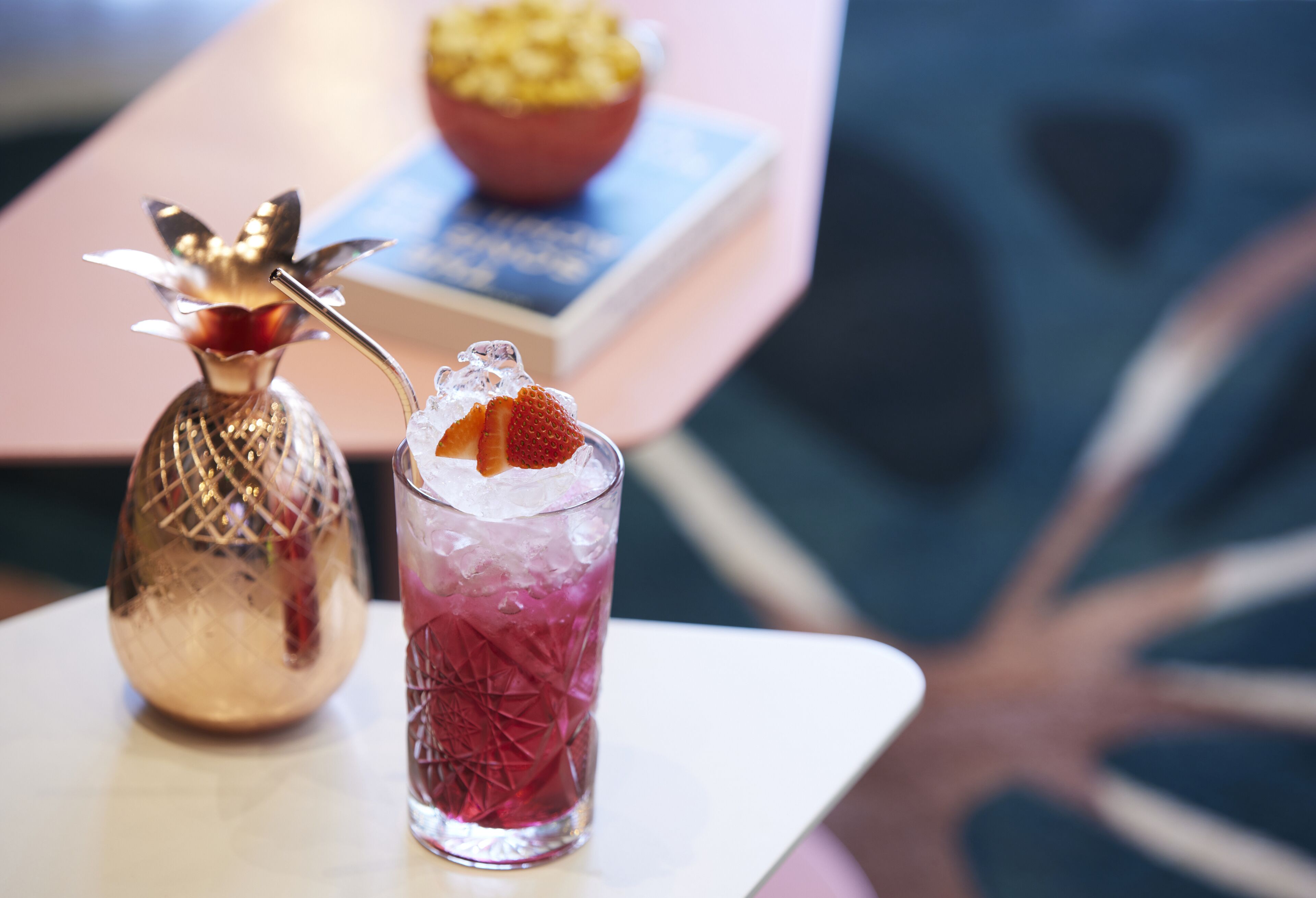 Una mesa con una bebida en un vaso y una botella decorativa.