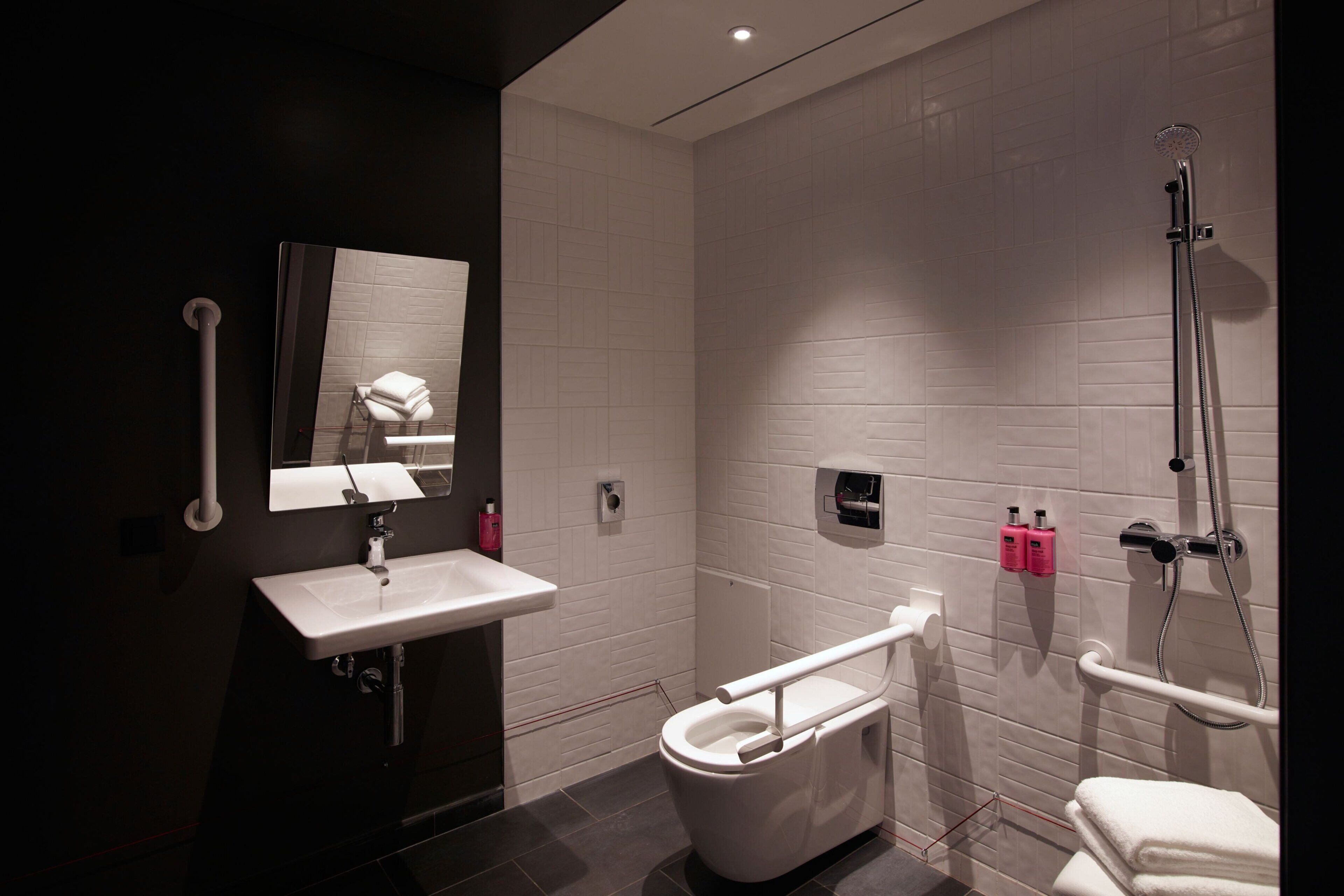A modern bathroom with a white sink, a toilet, and a shower.