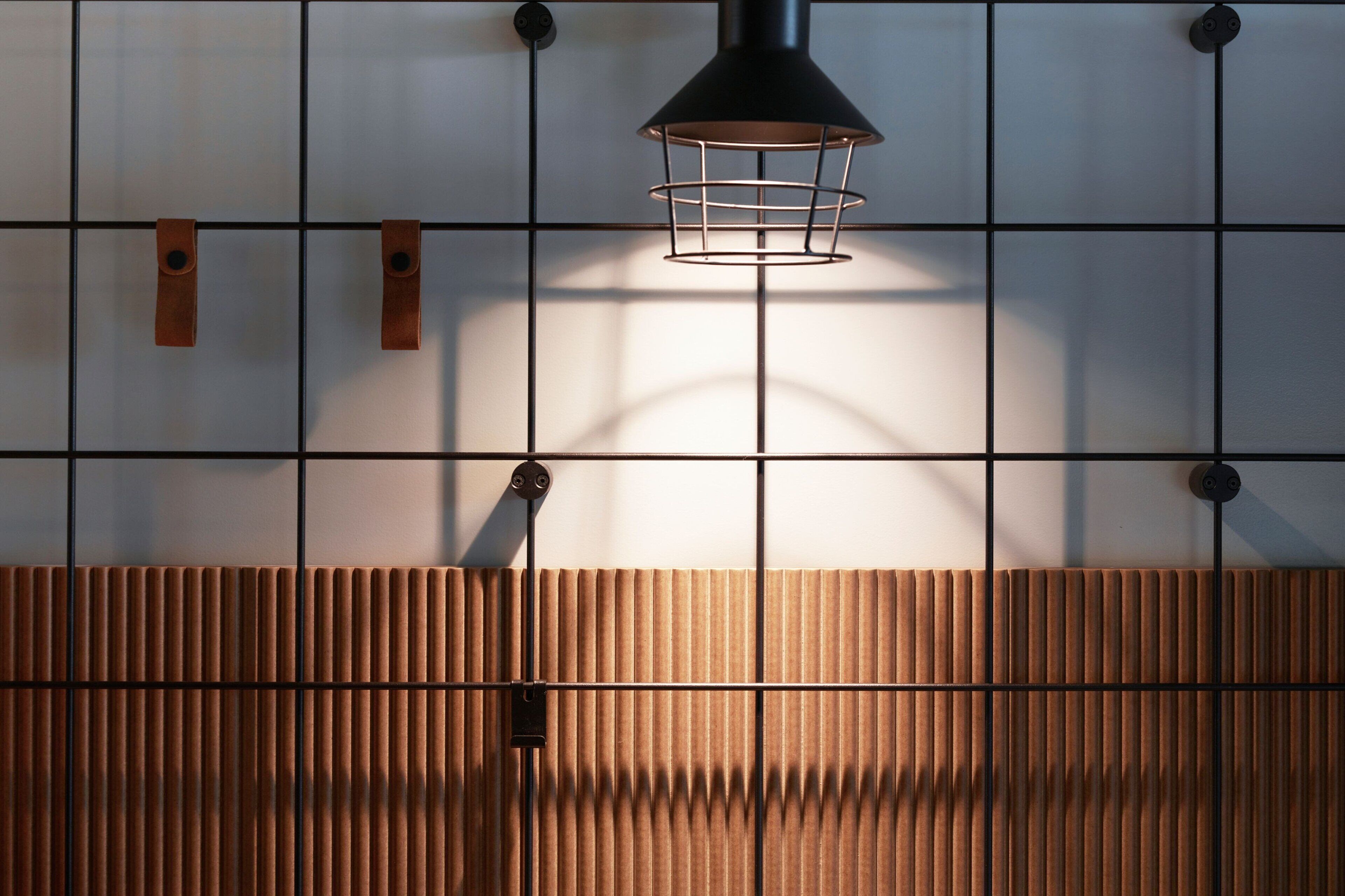 Un interior moderno con una pared de diseño en cuadrícula, un panel de madera en la parte inferior y una lámpara colgante.