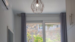 Et lille, lyst værelse med et vindue, et skrivebord, en stol og en pendel.