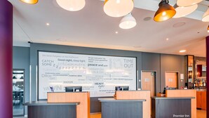 Ein Hotel-Rezeptionsbereich mit drei Theken, einer großen Wand mit Texten und Formulierungen rund um Schlaf und Entspannung, und einem Barbereich im Hintergrund.