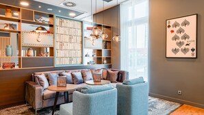 Ein stilvoller Lounge-Bereich mit einer Couch, Sesseln, einem Couchtisch und einem Bücherregal.