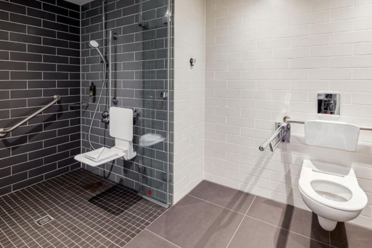 A modern bathroom with a glass shower enclosure, a white toilet, and a tiled floor.