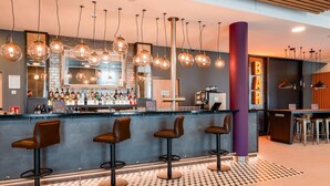 Eine Bar mit einer Theke, Hockstühlen und hängenden Pendelleuchten.