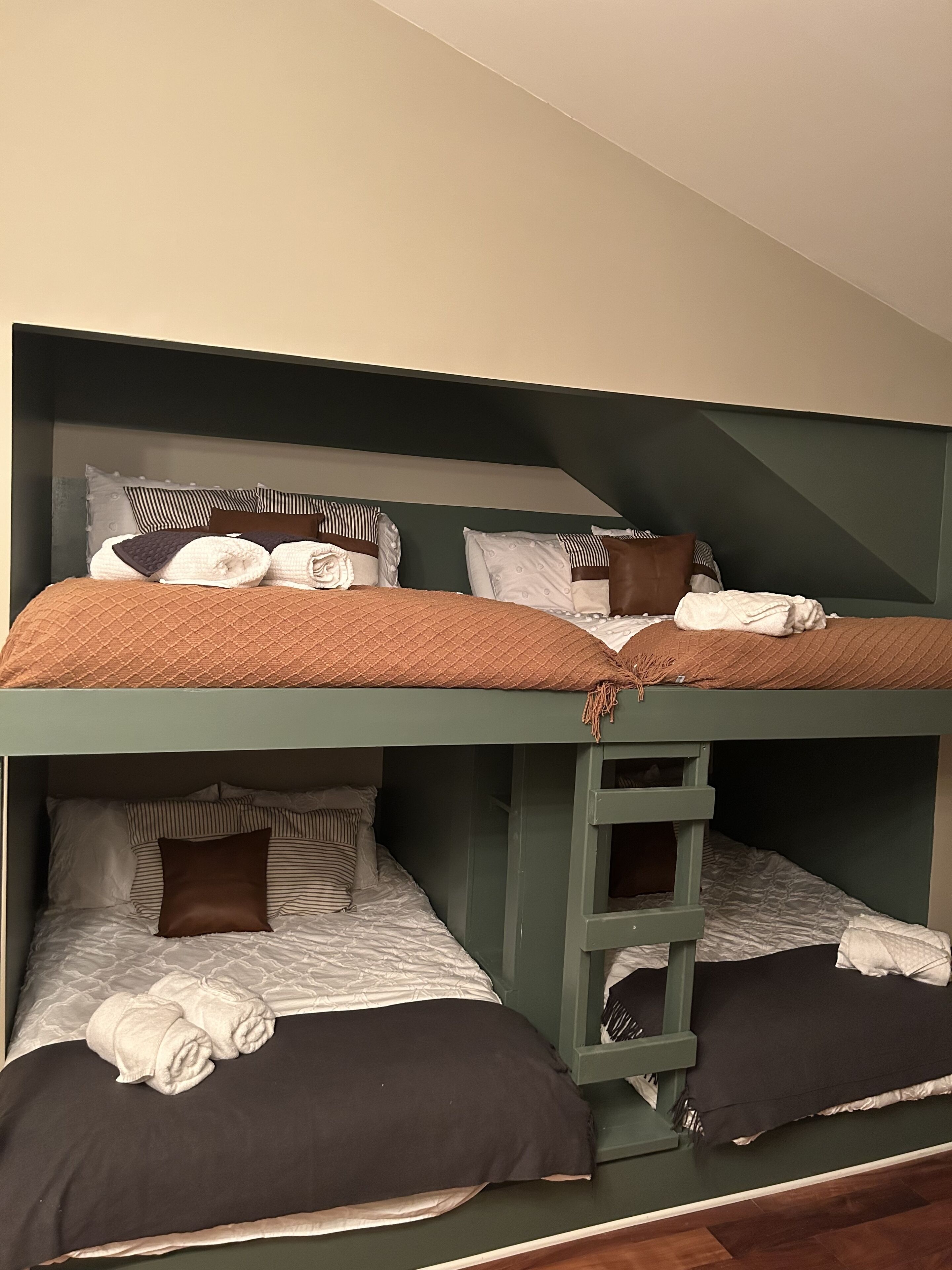 Une chambre avec un lit superposé à deux niveaux, chaque niveau étant équipé d’oreillers et de couvertures.