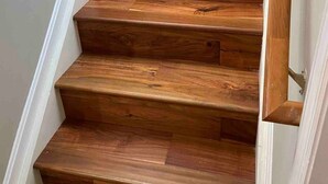 A wooden staircase with white walls.
