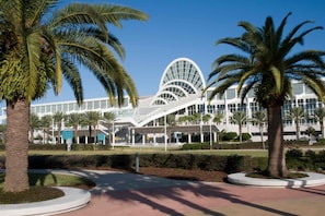 A modern building with a distinctive curved glass facade, surrounded by palm trees and a landscaped area. - 152 Watersong (Davenport)