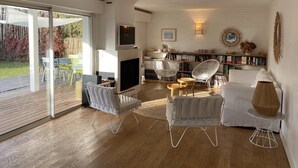 A modern living room with a fireplace, bookshelves, and a TV. - Magnificent villa with swimming pool in the center of Cap Ferret (CAP FERRET)
