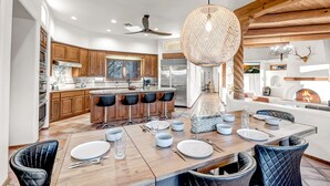 A modern kitchen with wooden cabinets, a central island with bar stools, and a dining area set for six with a large wooden table. - Private Pickleball Ct and Pool, Luxury North Scottsdale.  Mt Biking Trails close (Scottsdale)