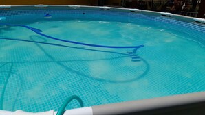 Una piscina con suelo de baldosas azules y una escalera visible.