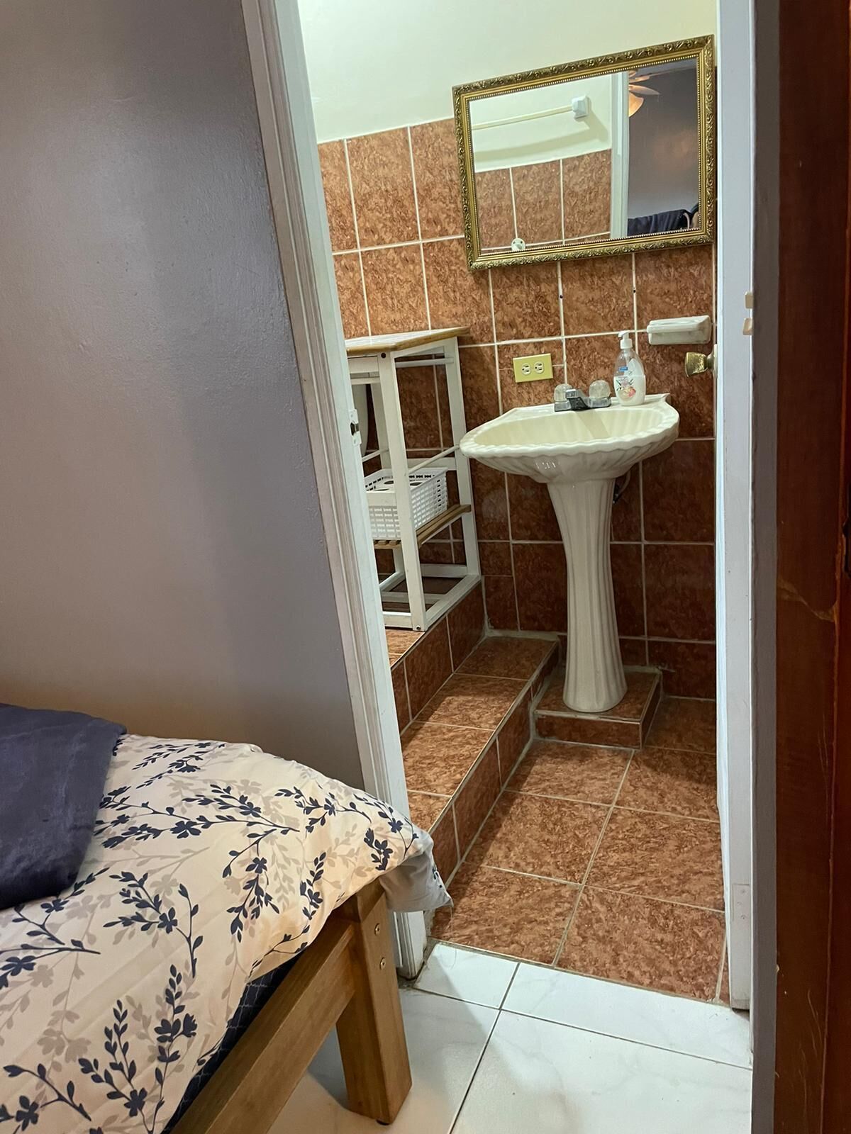 A small bathroom with a sink, mirror, and tiled walls.