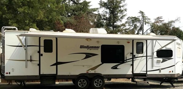 A Windjammer Rockwood RV with a side entrance, a small window, and a black awning. - Finegold Escape (North Fork)