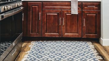 Een keuken met houten kastjes, een fornuis, een spoelbak en een blauwe betegelde achterwand.