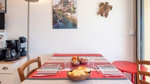 A dining area with a table set for two, a coffee maker, a basket of bread, and a bowl of nuts. - Primavéra by Interhome (Lacanau)