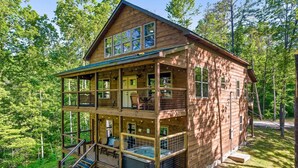 Una cabaña de madera de varios niveles con balcones, un jacuzzi y una terraza.