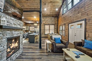 Un interior acogedor con chimenea de piedra, pisos de madera, sofás de cuero y un comedor.