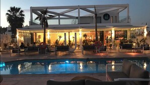 Un hotel modern amb piscina, zona d'estar a l'aire lliure i bar.