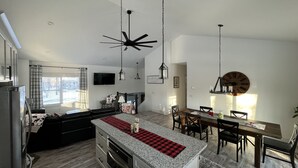 Eine moderne Küche mit Granit Arbeitsplatten, ein Essbereich mit Holztisch und -stühlen sowie ein Deckenventilator.