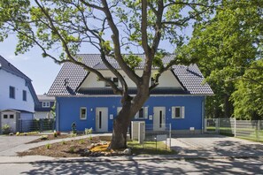 A residential building with a blue facade, a tiled roof, and a tree in the front yard. - Vacation home Luna - Holiday home Luna semi-detached house (Breege)