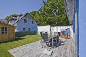 A patio with a table and chairs, a wooden shed, and a house with a blue exterior. - Vacation home Luna - Holiday home Luna semi-detached house (Breege)