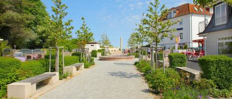 A paved pathway leading to a central plaza with benches and greenery.