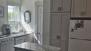 A modern kitchen with white cabinetry, a central island, and a built-in oven.